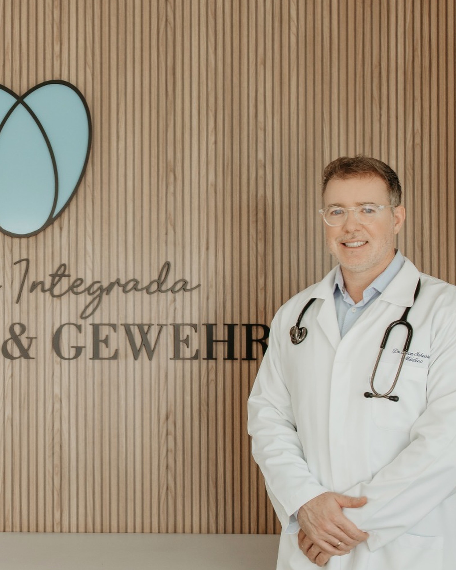 Médico da clínica diante do símbolo da marca