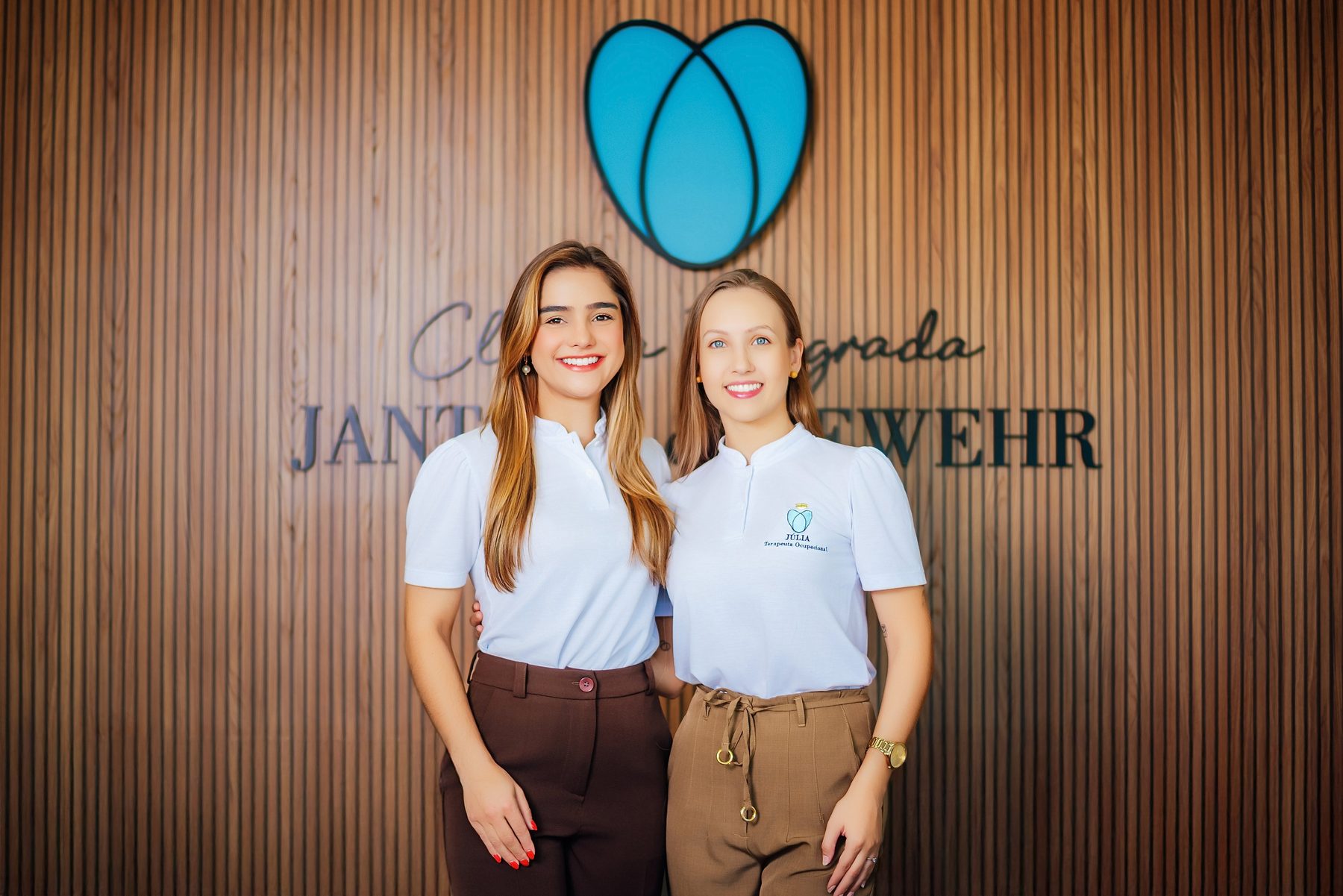 Marina Severo Jantsch e Júlia Gewehr diante do símbolo da clínica